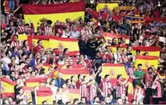  ?? AFP ?? Atletico Madrid fans hold up Spanish flags during the match against Barcelona in Madrid on Saturday.