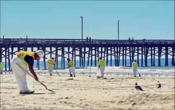  ?? Jeff Gritchen / Associated Press ?? Workers clean oil from the sand in Newport Beach, California, on Tuesday.