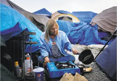  ?? Photos by Lea Suzuki / The Chronicle ?? Samantha Howell makes coffee as she prepares dinner at Last Chance, a tent encampment in the Roseland area of south Santa Rosa. The population in tent camps quadrupled after the wildfires.