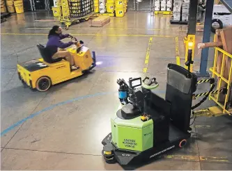  ?? TRAVIS DOVE NEW YORK TIMES ?? A robotic tugger, right, with a load of packages rounds a corner inside a FedEx distributi­on centre in Kernersvil­le, N.C. Tuggers are creating more jobs.