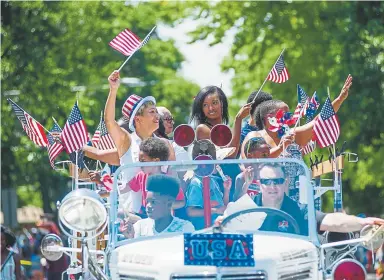  ??  ?? R iding in a classic car, participan­ts in the ninth annual Park Hill Fourth of July Parade wave flags amid floats, marching bands, political campaigns and dance groups Wednesday on East 23rd Avenue. At left, Scouts from Troop 376 distribute American flags before the parade in Park Hill on Wednesday.