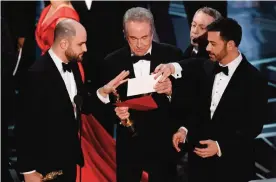  ??  ?? ‘La La Land’ producer Jordan Horowitz, left, presenter Warren Beatty, center, and host Jimmy Kimmel right, look at an envelope announcing ‘Moonlight’ as best picture at the Oscars at the Dolby Theatre in Los Angeles. — AP