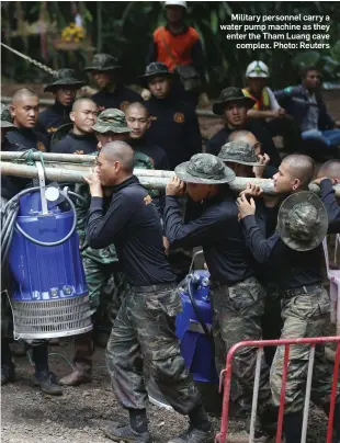  ?? Photo: Reuters ?? Military personnel carry a water pump machine as they enter the Tham Luang cave complex.