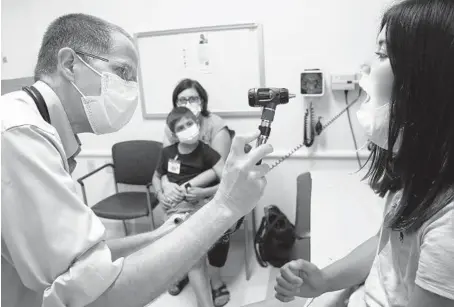  ?? ANTONIO PEREZ/CHICAGO TRIBUNE PHOTOS ?? Juliana Gometz, 11, is examined by Dr. Bill Muller while her mother, Shannon Lightner-Gometz, and brother Gabriel look on at Lurie Children’s Hospital in Chicago on Aug. 27.
