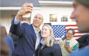  ?? PATRICK SEMANSKY/AP ?? Democratic presidenti­al candidate Sen. Cory Booker, D-N.J., takes a selfie with an attendee after speaking at a campaign event Jan. 7 at a Democratic Party official’s home in Des Moines, Iowa.