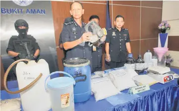  ??  ?? Kang and his officers show the seized drugs and the drug processing equipment during a press conference in Bukit Aman. — Bernama photo