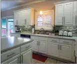  ??  ?? The kitchen is   tted with painted cabinetry, glasstile backsplash­es and solid-surface counters.