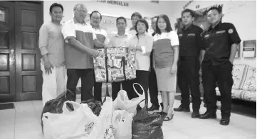  ??  ?? Yii presents the seized goods to Anthony. At respective third and fourth left are MRC Kapit chapter chairman Dr Sia Tih Kong and KDC secretary Yong Ing Chu.