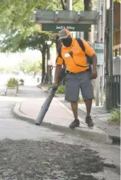  ??  ?? Thomas Jacoway uses a leaf blower to clean the streets.