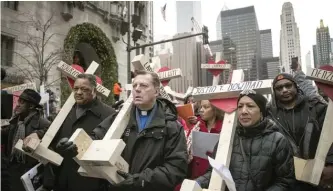  ??  ?? The Rev. Michael Pfleger led a New Year’s Eve march in 2016 down Michigan Avenue in which protesters carried crosses with the names of 2016 murder victims. This year, Pfleger plans to repeat the march, but this time, he says protesters will carry Chicago flag replicas riddled with bullet holes and “dripping” with blood.