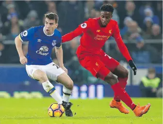 ??  ?? Everton’s Seamus Coleman, left, tries to elude the tackle of Liverpool’s Divock Origi during English Premier League action at Goodison Park in Liverpool on Monday.