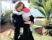 ??  ?? Merencia Scholtz lavishes affection on one of the babies in her care. She and her husband fill a crucial void.