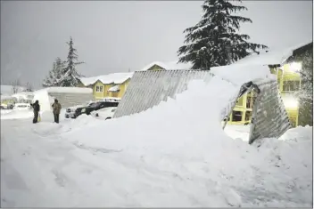  ?? ELIAS FUNEZ /THE UNION ?? A PAIR OF RESIDENTS AT THE CEDAR PARK APARTMENTS in Grass Valley, Calif., take a break from shoveling snow during Tuesday evening’s blizzard conditions that caused widespread damage to the Sierra Nevada, including these awnings, which buckled from the snow.