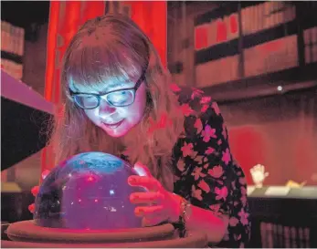  ?? FOTO: VICTORIA JONES/DPA ?? Die Faszinatio­n der Magie: Eine Besucherin der Harry-Potter-Ausstellun­g schaut in eine Kristallku­gel, in der die Zukunft visuell dargestell­t wird.