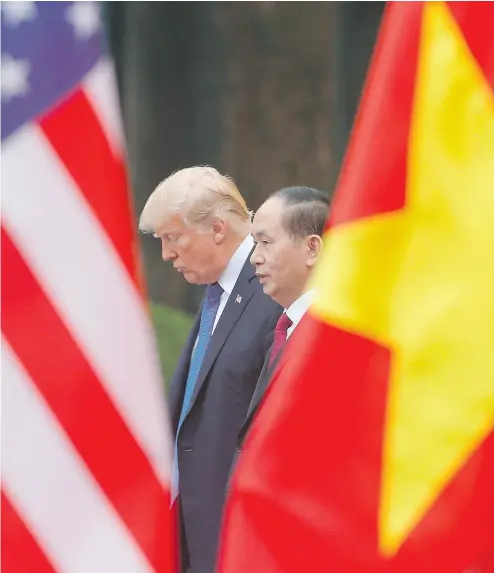  ?? KHAM / POOL / AFP / GETTY IMAGES ?? Flanked by their flags, U. S. President Donald Trump and Vietnam’s President Tran Dai Quang attend a joint press conference Sunday in Hanoi.