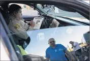  ?? Katie Falkenberg Los Angeles Times ?? DEPUTY Ivan Davanzo fills out a report after a burglary call from James Oakes, ref lected in the window.