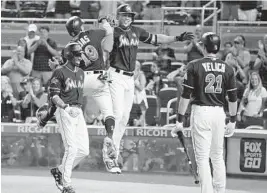  ?? WILFREDO LEE/AP ?? Miami’s Giancarlo Stanton, second from right, celebrates with teammates after he hit a home run scoring Miguel Rojas (19) and Dee Gordon, left.