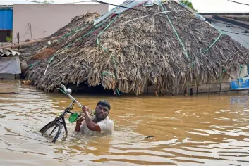  ??  ?? MOVING TO A SAFE PLACE: A man carries his cycle as he wades across a flooded locality in Vijayawada, Andhra Pradesh, on Saturday. —