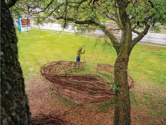  ??  ?? Artist Ibraim Nascimento weaves together branches with Fatuma Christine Emedi as they and other community members create a giant nest at Westbury United Methodist Church. The nest is reminiscen­t of a tomb and has sat in front of the church during Holy Week. On Easter, community members will fill the nest with flowers.