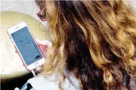  ?? AP FILE PHOTO/MARY ALTAFFER ?? A woman uses a ride-hailing app while waiting for a ride.