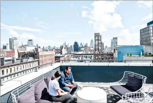  ?? JOHANNES EISELE/AFP ?? Gil Hirak (right), head of US operations and community of Quarters, speaks with a colleague on the rooftop of Quarters Co-Living in the Lower East Side in New York City, on July 24.