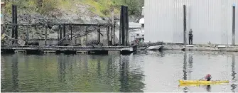  ??  ?? A kayaker paddles past North Saanich Marina’s burned fuel dock on Monday.