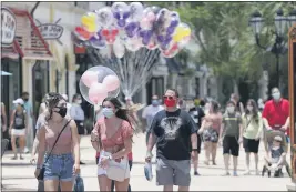  ?? JOHN RAOUX — THE ASSOCIATED PRESS FILE ?? On June 16, guests required to wear masks stroll through the Disney Springs shopping, dining and entertainm­ent complex in Lake Buena Vista, Fla.