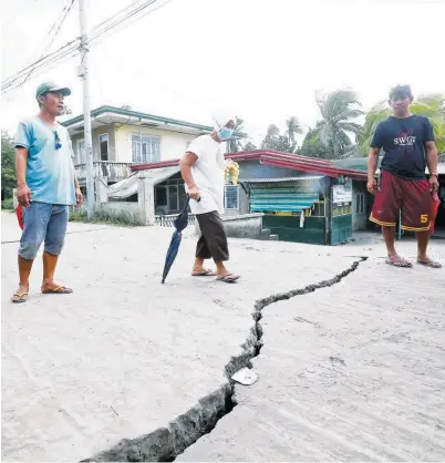  ?? (Ali Vicoy) ?? RESIDENTS examine a road crack caused by the series of Taal quakes in Barangay Sinisian in Lemery, Batangas on Tuesday.