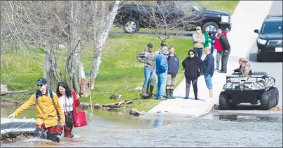  ?? CP PHOTO ?? Simon Barton, left, and Chelsea Burley wear makeshift waders of garbage bags and packing tape as they cross a flooded road in Saint John, N.B., on Sunday.