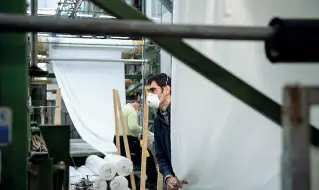  ??  ?? Lavoro e protezioni Un operaio del comparto tessile durante un turno di lavoro con mascherina