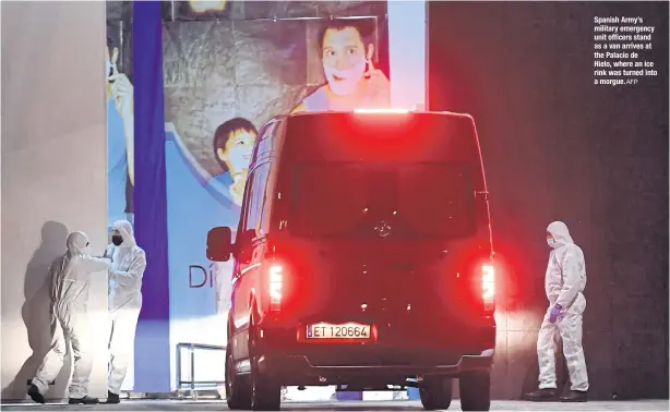  ?? AFP ?? Spanish Army’s military emergency unit officers stand as a van arrives at the Palacio de Hielo, where an ice rink was turned into a morgue.