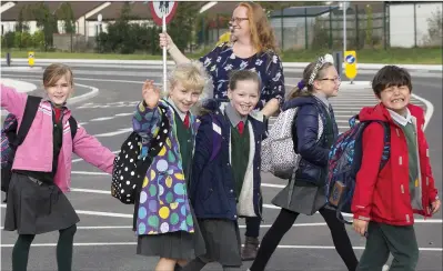  ??  ?? Doreen McHale acts as lollipop lady as the children walk from the old Ravenswell school to the new one.
