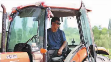  ?? PHOTOS BY CHEN ZEBING / CHINA DAILY ?? Hai Fugui, a migrant from Minning town, drives a tractor at Lilan Winery, at the foot of Helan Mountains in Ningxia Hui autonomous region, on June 11.