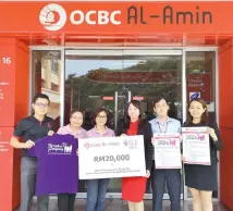  ??  ?? OCBC staff holding a mock cheque for Walk-a-Payung Family Day.