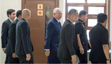  ??  ?? Najib (centre) seen at the Sessions Court where he was charged with altering the 1MDB final report. — Bernama photo
