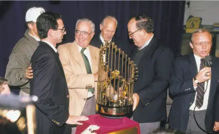  ?? Focus on Sport / Getty Images 1989 ?? Commission­er Fay Vincent (second right) hands the World Series trophy to A’s owner Walter A. Haas Jr. and Wally Haas (left).