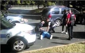  ?? THE ASSOCIATED PRESS ?? Charlotte police squat next to Keith Lamont Scott as Scott lies face-down on the ground Tuesday in Charlotte, N.C. In the video of the deadly encounter between Charlotte police and the black man, Rakeyia Scott repeatedly tells officers her husband is...