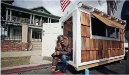  ?? AP ?? Irene "Smokie" McGhee, a woman who had been sleeping on the streets in a South Los Angeles neighborho­od, listens to music on the doorway of her newly built tiny home.