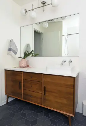  ??  ?? ABOVE LEFT: A MIDCENTURY-STYLE MEDIA CONSOLE FROM WEST ELM WAS ADAPTED INTO A SLEEK VANITY IN THE MAIN BATHROOM.