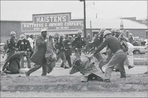  ?? (File Photo/AP) ?? A state trooper swings a billy club at John Lewis (right foreground), chairman of the Student Nonviolent Coordinati­ng Committee, to break up a civil rights voting march in Selma, Ala., on March 7, 1965. The March 7, 2021, Selma Bridge Crossing Jubilee will be the first without the towering presence of Lewis, as well as the Rev. Joseph Lowery, the Rev. C.T. Vivian and attorney Bruce Boynton, who all died in 2020.