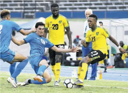  ?? (Photo: Naphtali Junior) ?? Jamaica’s Alex Marshall (right) comes under pressure from Aruba’s Annuar Kock (second left) and Glenbert Croes (left) during the Concacaf Nations League match inside National Stadium on Saturday. Looking on is Marshall’s teammate Kemar Lawrence.