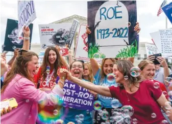  ?? AP PHOTO/GEMUNU AMARASINGH­E ?? Anti-abortion protesters celebrate Friday following the Supreme Court’s decision to overturn Roe v. Wade, which provided a federally protected right to abortion, outside the Supreme Court in Washington.