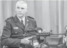  ?? ASSOCIATED PRESS ?? Police Sr. Sgt. Paddy Hannan shows New Zealand lawmakers in Wellington an AR-15 style rifle similar to one of the weapons a gunman used to slaughter 50 people at two mosques.
