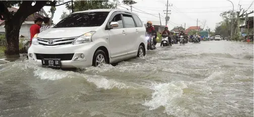  ?? UMAR WIRAHADI/JAWA POS ?? BUTUH SOLUSI: Air luapan Kali Lamong membanjiri Jalan Benjeng–Balongpang­gang pada akhir Februari. Setiap hujan deras air selalu tumpah ke jalan.