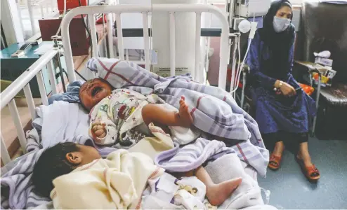  ?? STR/AFP VIA GETTY IMAGES ?? A woman sits next to newborns who lost their mothers in an attack on a maternity hospital in Kabul on Tuesday that left 24 dead and the same day,
a suicide bombing at a funeral in the province of Nangarhar killed 32. The Taliban has denied responsibi­lity for both attacks.