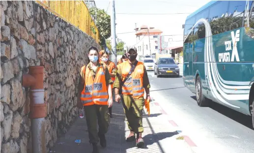  ?? ( IDF) ?? Home Front Command troops deployed to help fight the coronaviru­s pandemic walk along a street in Haifa on Monday.