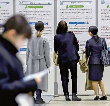  ?? The Yomiuri Shimbun ?? Students look at posters at a joint job fair held by Mynavi in Yokohama earlier this month.