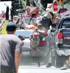  ?? RYAN M. KELLY / THE DAILY PROGRESS VIA THE ASSOCIATED PRESS FILES ?? People fly into the air as a vehicle drives into a group of protesters demonstrat­ing against a white nationalis­t rally in Charlottes­ville, Va. last August.