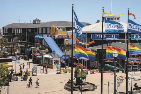  ?? Santiago Mejia / The Chronicle ?? Flags are flying cheerily, but visitors have no trouble social distancing at Pier 39 on Tuesday as tourists stay away.