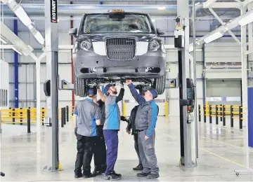  ?? — Reuters photo ?? Workers inspect an electric taxi at The London Taxi Company’s new facility near Coventry in England.